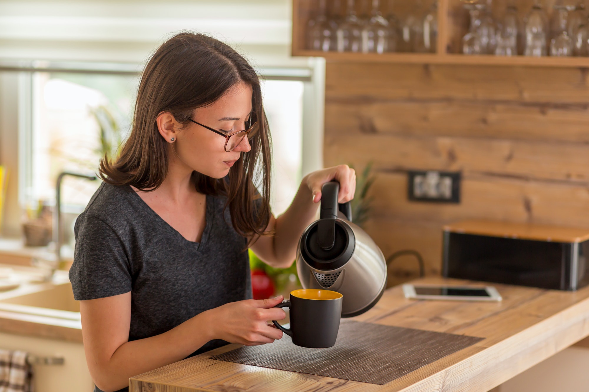 Woman pouring a cup of coffee in the morning at home