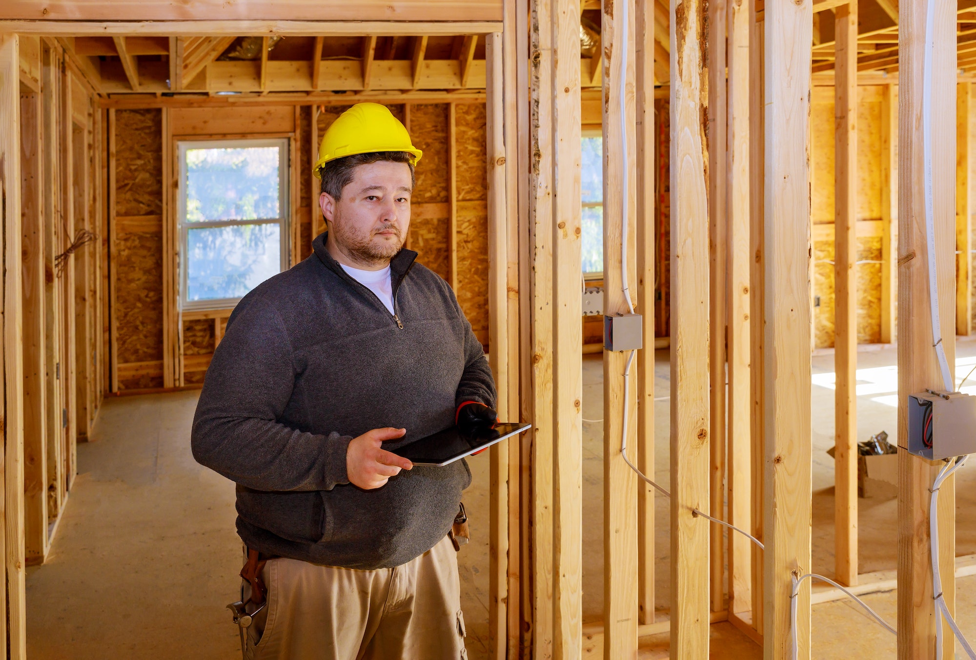 Inspector checking building during house construction in the tablet PC with hard hat